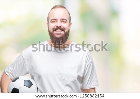 Young caucasian hipster man holding soccer football ball over isolated background with a happy face standing and smiling with a confident smile showing teeth