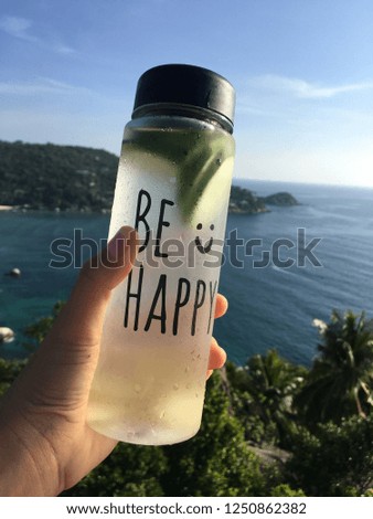 Healthy drink bottle in hand with ocean view