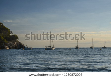 Sailboats anchored in a bay in Menorca, at sunset