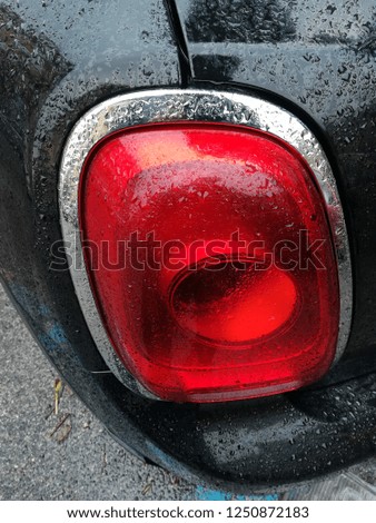 Black car rear headlight washed by rain, in detail