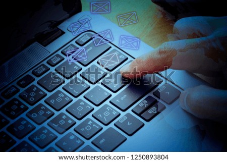 communication concept; vintage style picture of close up single finger press button on laptop keyboard in office space. send email to everybody in the world
