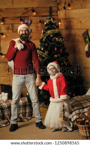 Santa claus kid and bearded man at Christmas tree. Christmas happy child and father with toy. Winter holiday and vacation. Xmas party celebration, fathers day. New year small girl and man, fairytale.