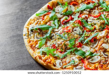 vegetarian Pizza with Mozzarella cheese, mushrooms, tomato sauce, pepper, Spices and Fresh arugula. Italian pizza on wooden table background