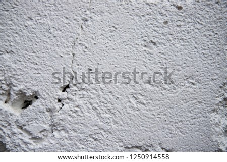 Painted wall with grungy texture closeup photo. White plaster brushed texture. White concrete wall. Greek architecture background. Pottery house wall. White painted surface. Vintage or shabby chic