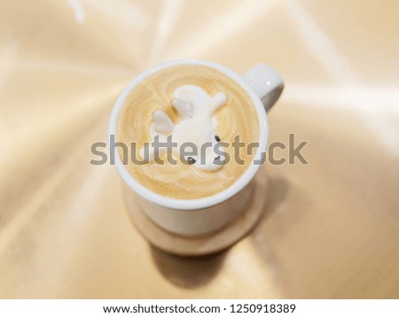 Close up white cup of Coffee with a decorated elk on top, Coffee latte on the table, Christmas coffee concept.