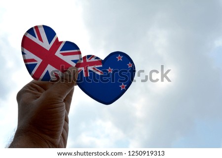 Hand holds a heart Shape United Kingdom and New Zealand flag, love between two countries