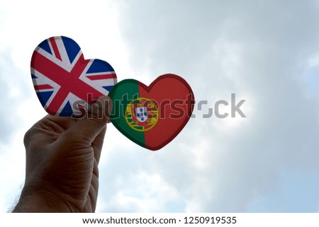 Hand holds a heart Shape United Kingdom and Portugal flag, love between two countries