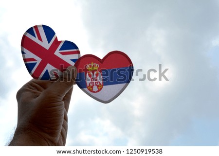 Hand holds a heart Shape United Kingdom and Serbia flag, love between two countries