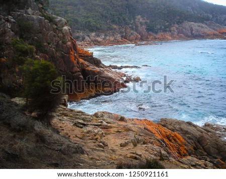 The ocean splashing onto the red rocks of the coastline
