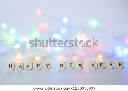 Happy New Year. Cubes with letters on a light surface on the background of Christmas lights. Winter holidays.                  