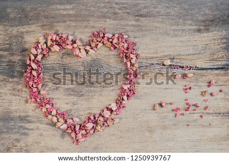 Mexican Creeper (Antigonon Leptopus) or Coral Bells, coral vine, Coralita, bee bush or San Miguelito vine, pink petals shape heart on wood background.