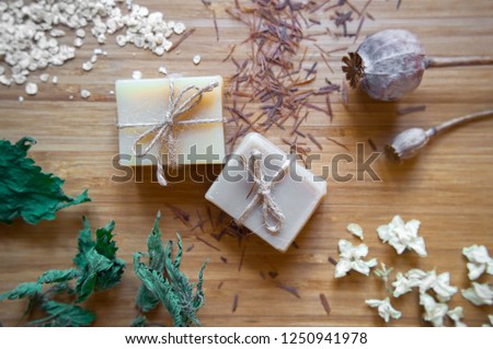 Bars of handmade natural Soap with dried flower blossoms, oats and organic ingredients on rustic wooden background. Original handmade gift herbal soap for bath and spa treatment. Top view, Beauty. Royalty-Free Stock Photo #1250941978
