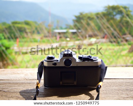 Vintage film camera stand on the wooden table with blur nature background in Nan, Thailand