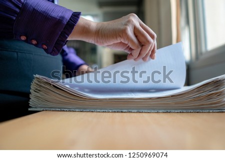 The hand of a woman holds important documents in the office.