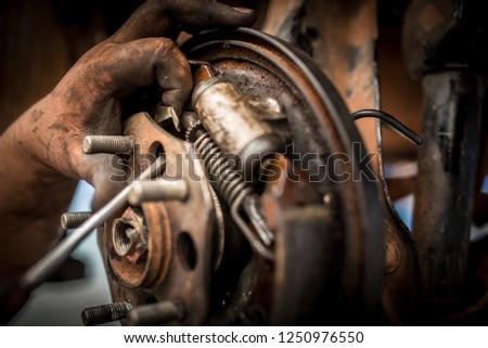 mechanic hands are fixing old rusted drum brake and disc brake mechanism of car by hand