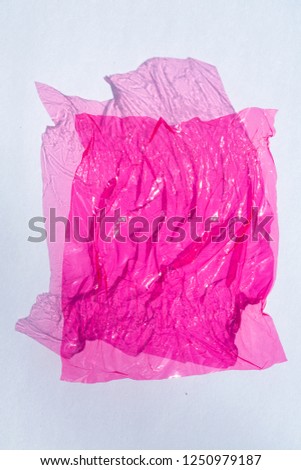 Thin sheet of pink colour cellophane with shiny crumpled surface texture  on white background, Abstract, Light & Shadow concept