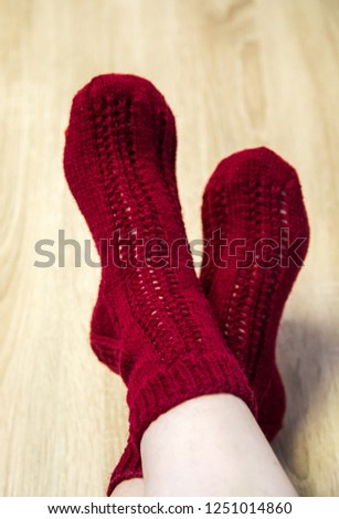 A woman wearing warm hand craft socks. Knitted form a natural sheep wool yarn. Winter clothing. On a wooden background.