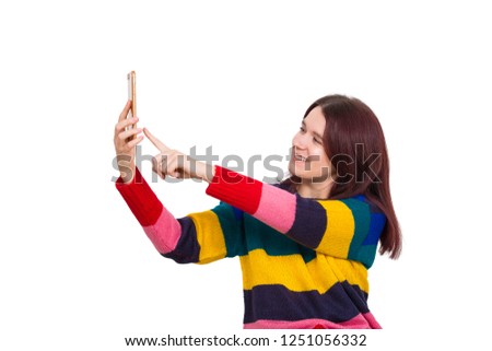 Beautiful young woman wearing colorful sweater pointing finger to phone screen to take a selfie. Positive emotion, life joy and happiness isolated over white background.