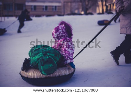 children slide downhill on a winter day