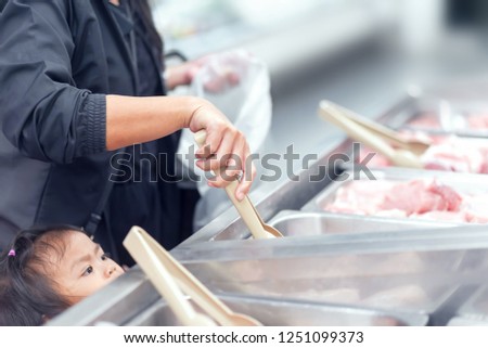 Soft focus from night photography & noise reduction used to abstract or background concept, Expression of happy family in food store, Mom picking meat with her daughter.
