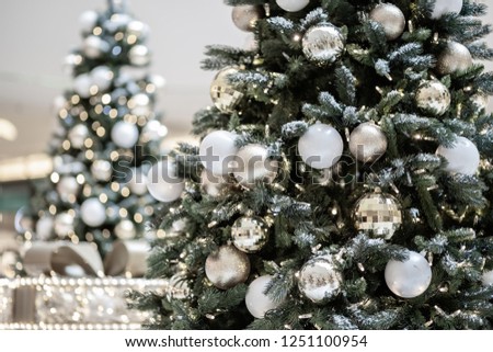 Christmas tree with festive decor against blurred fairy lights. New Year balls and garland against the background of blurred tree branches. Background holiday bokeh, toned image