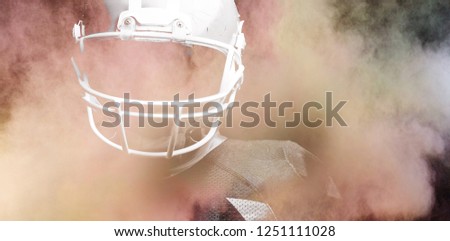 Splashing of color powder against american football player standing with rugby helmet