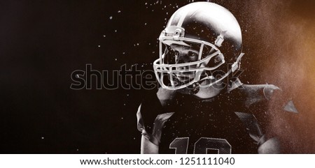 Digitally generated image of powder against american football player standing with rugby helmet