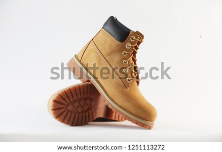 A pair of yellow leather boots on a white background. This kind of boot is very popular in autumn and winter for its fashionable style.