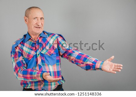 The elderly person point away. Serious Mature man pointing finger to the side, on grey background, copy space.