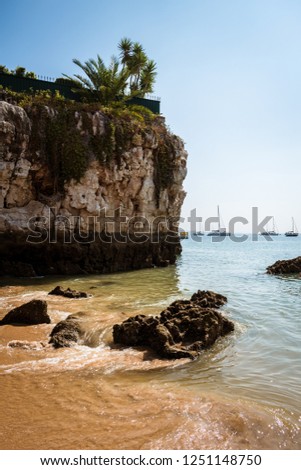 The Praia da Rainha (Queen's beach) in Cascais. Paradise between cliffs surrounded by the Atlantic Ocean in Cascais, district of Lisbon, Portugal with boats / yachts in the background. Royalty-Free Stock Photo #1251148750