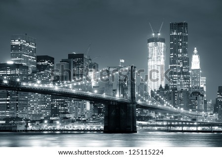 New York City Brooklyn Bridge black and white with downtown skyline over East River.
