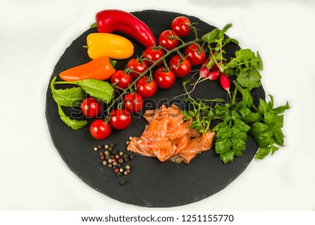 Composition of pasta fresh tomato, pepper, fish, radish on black stone board, white background.