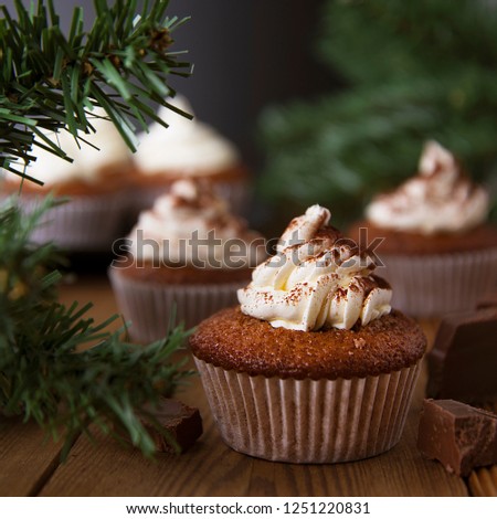 Chocolate cupcakes with whipped cream on rustic wooden table. Square image. Winter dessert. 