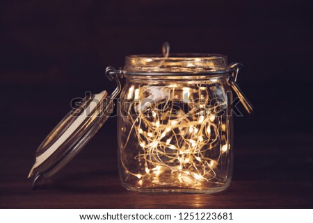 Yellow garland in jar on wooden background in dark. Concept New year.