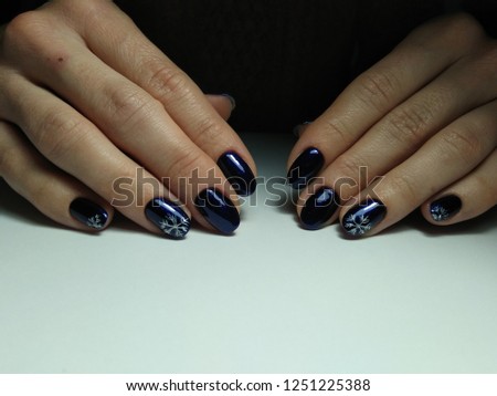 Deep blue color on nails with New Year designs. Snowflakes.