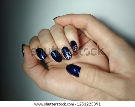 Deep blue color on nails with New Year designs. Snowflakes.