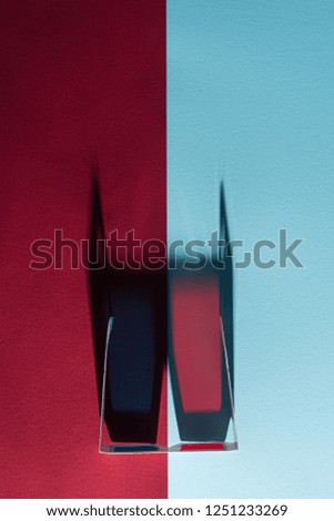 top view of cardboard 3d glasses with long vertical shadow on blue and bordo background