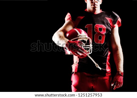 American football player holding rugby helmet against black background