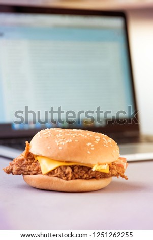 Improper nutrition in the form of a sandwich on the background of a laptop. Quick snack