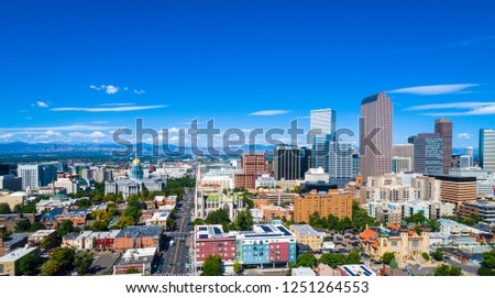 Aerial drone view of a wide panoramic view of the Denver , Colorado downtown skyline cityscape towers and skyscrapers rising on right and Colorado state Capitol building on left with Rocky Mountains
