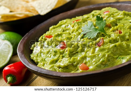 Guacamole with avocado, lime, tomato, and cilantro with tortilla chips. Royalty-Free Stock Photo #125126717