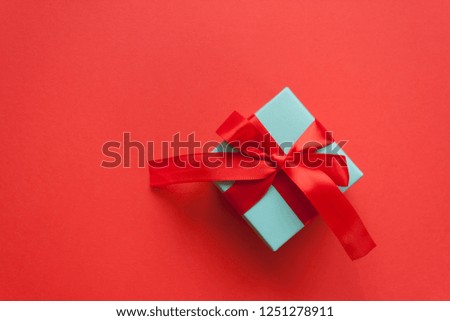 Blue gift tied with red ribbon on red background