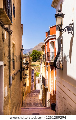 The cozy street of the old European city of Relleu is paved with cobblestones in the form of a picture. Mediterranean architecture in Spain.