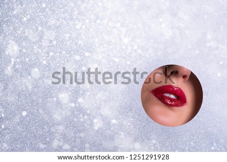 Beauty salon advertising banner with copy space. View of bright lips with glitter through hole in silver paper background. Make up artist, beauty concept. Ready to new year party. Cosmetics sale
