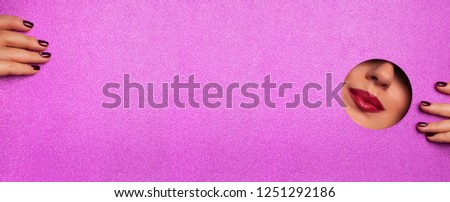 View of bright lips through hole in shimmer violet paper background. Make up artist, beauty concept. Ready to new year party. Cosmetics sale. Beauty salon advertising banner with copy space.