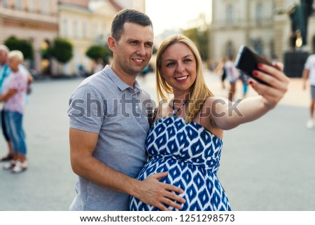 Expecting couple making photo on the street