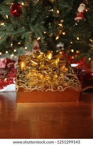 Gold Christmas Box with Gold Bow. Christmas Gift under a Christmas Tree. Holiday Gift. Golden Gift. 