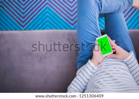 man is relaxing on comfortable couch and using smartphone at home