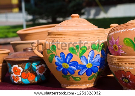 handmade and handpainted ceramic clay jugs, pots with covers, bright floral patterns, closeup photo