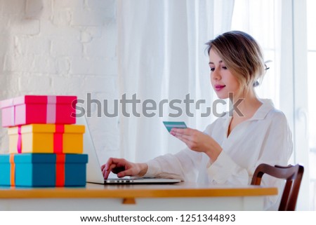 Young girl with holiday gifts and laptop computer holding a credit card. Business, education, shopping and other concept